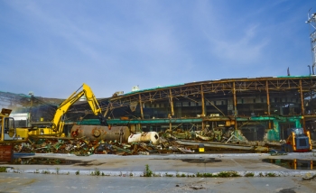 A shear-equipped excavator cuts beams to allow the roof to safely collapse. A shear-equipped excavator cuts beams to allow the roof to safely collapse.