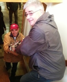 John Rizzo passes canned food to John Rendall to deliver to a food pantry. John Rizzo passes canned food to John Rendall to deliver to a food pantry.