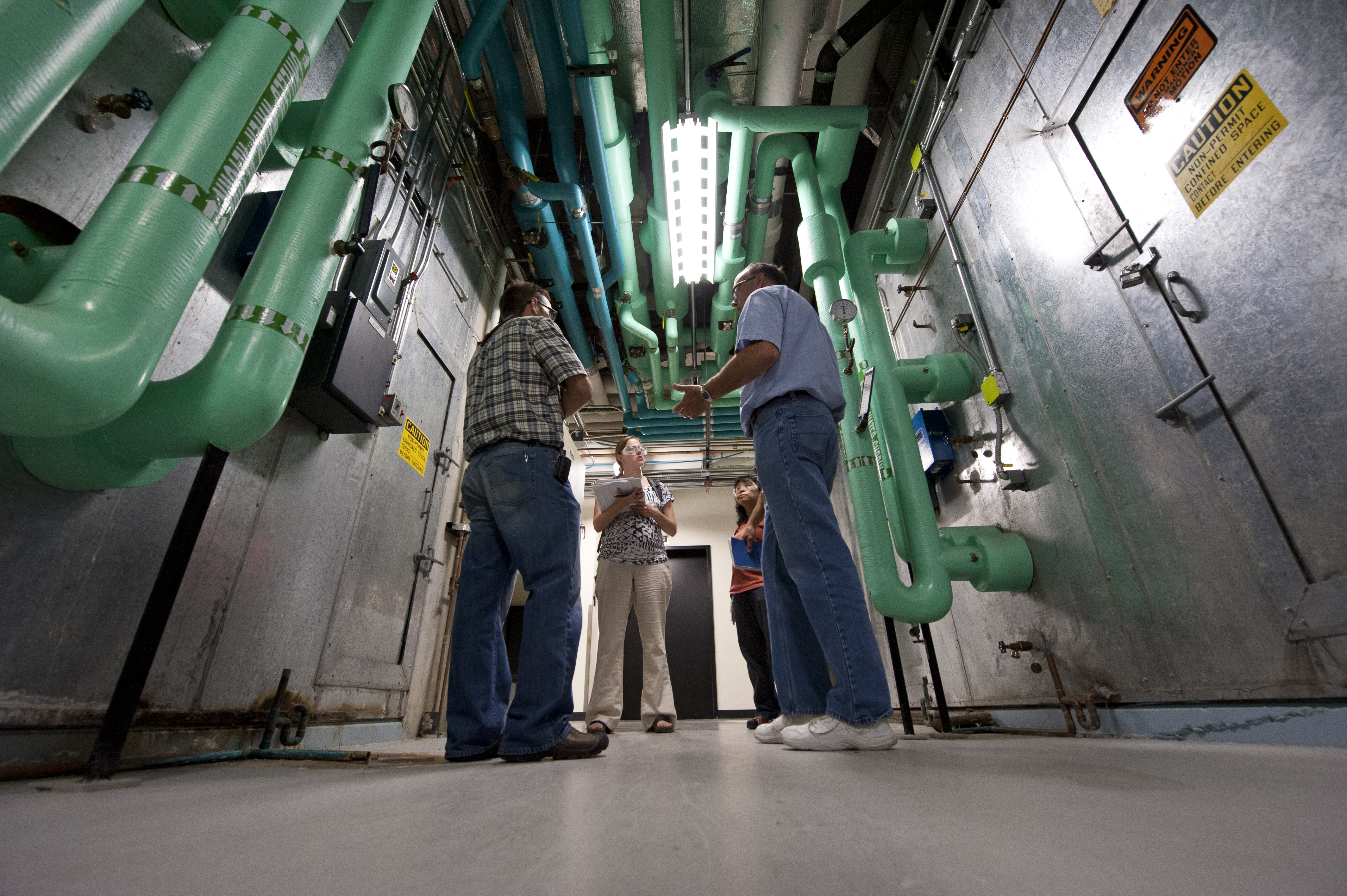 Three individuals speaking to each other in a group in a hallway.