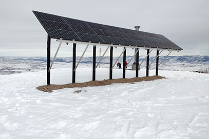 Photovoltaic panels on the roof with snow, with a snow shovel in