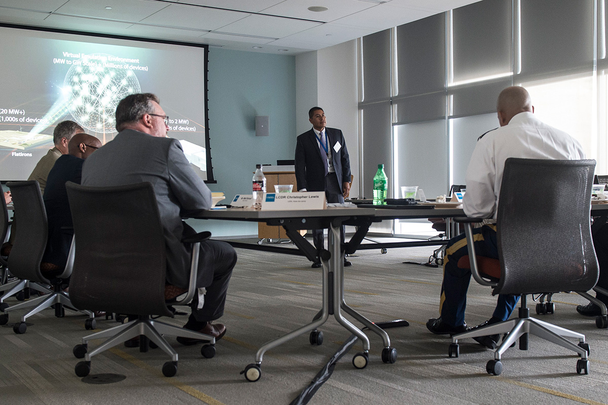 individuals sitting around a table listening to a presentation.