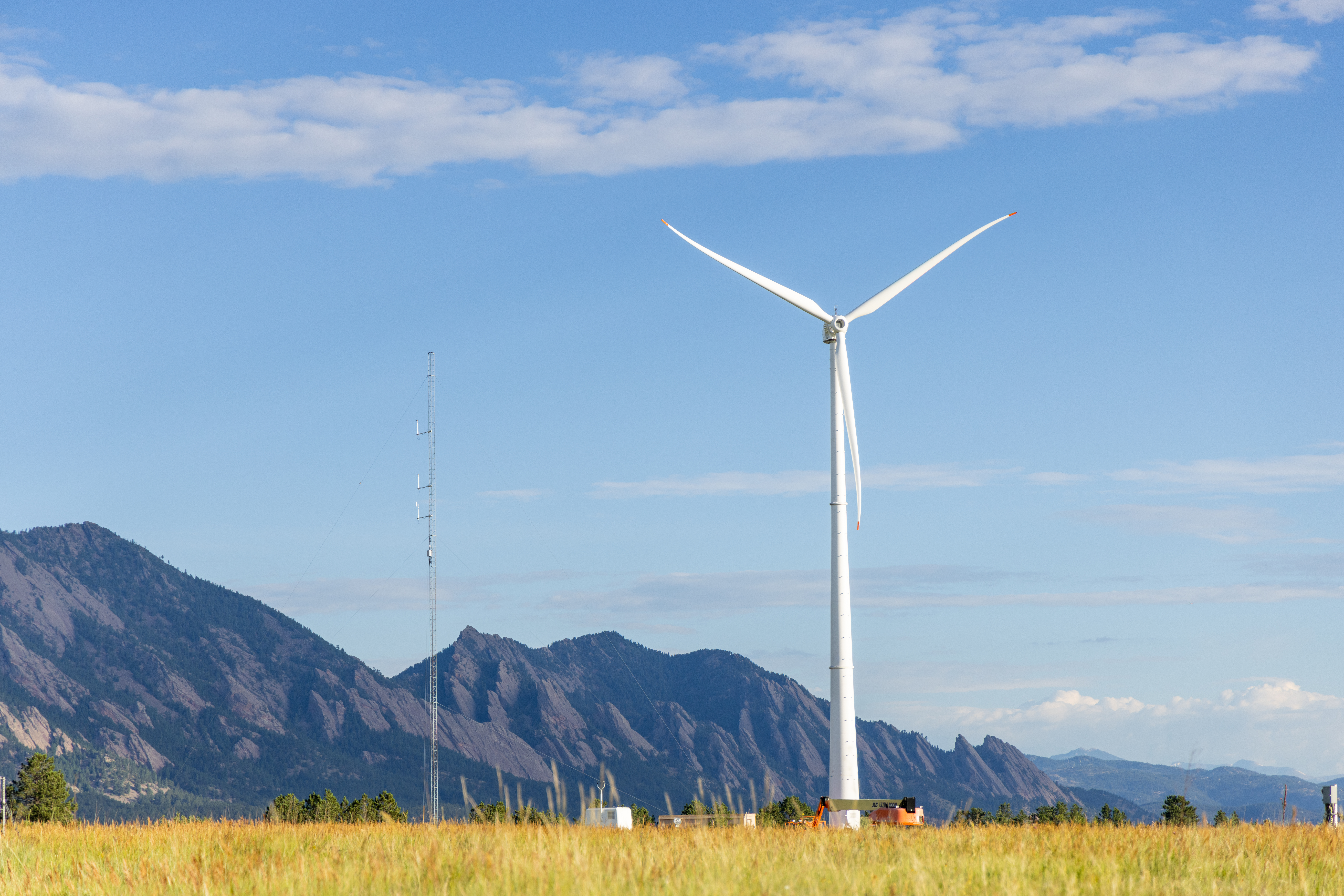 A wind turbine in a field near a mountain.