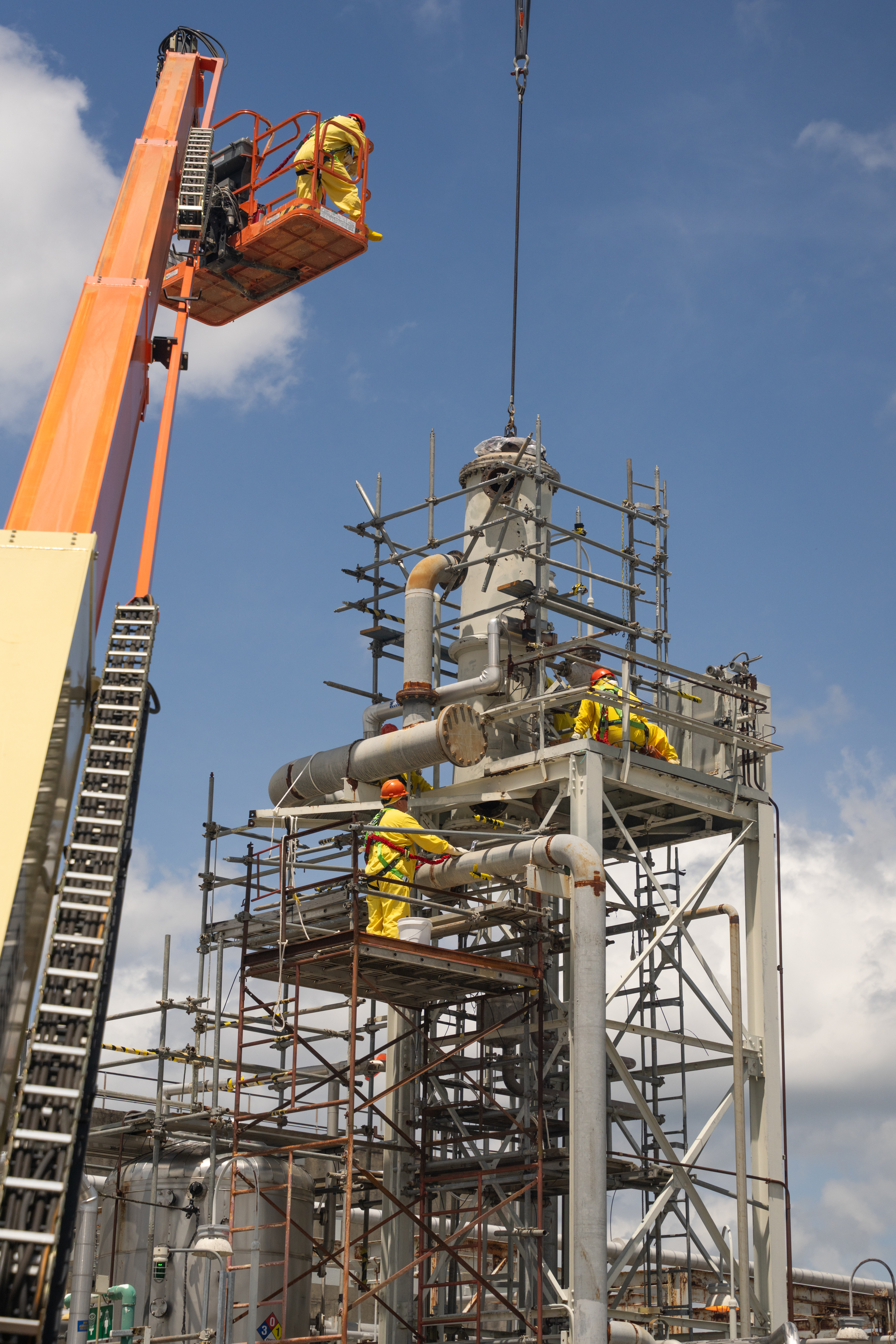 A crane and a tall tower with employees working on them