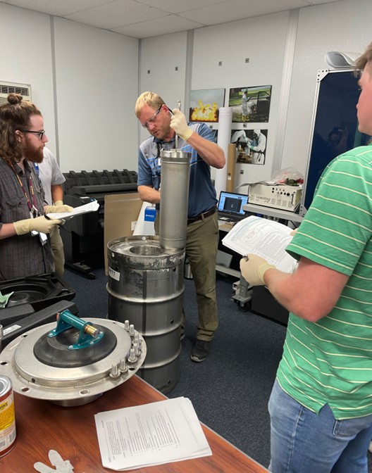 Employees in a room performing work on a round metal tank