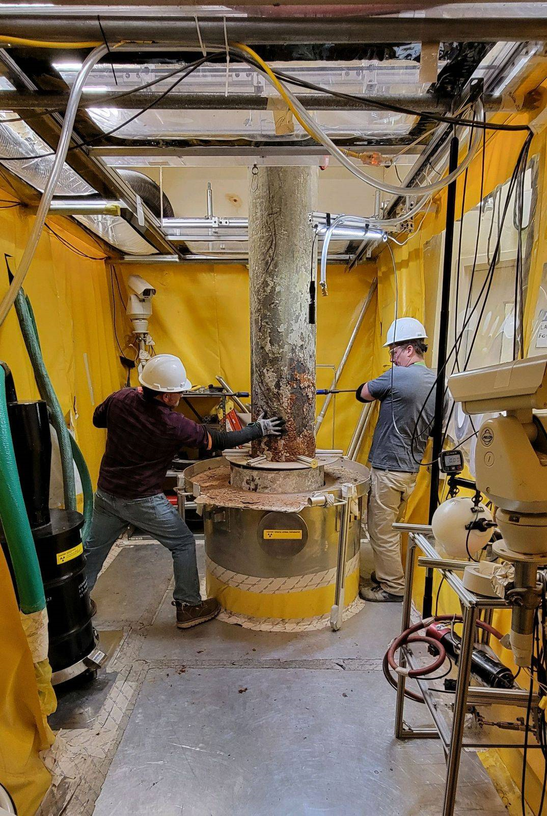 Two employees in hard hats working on a metal large machine