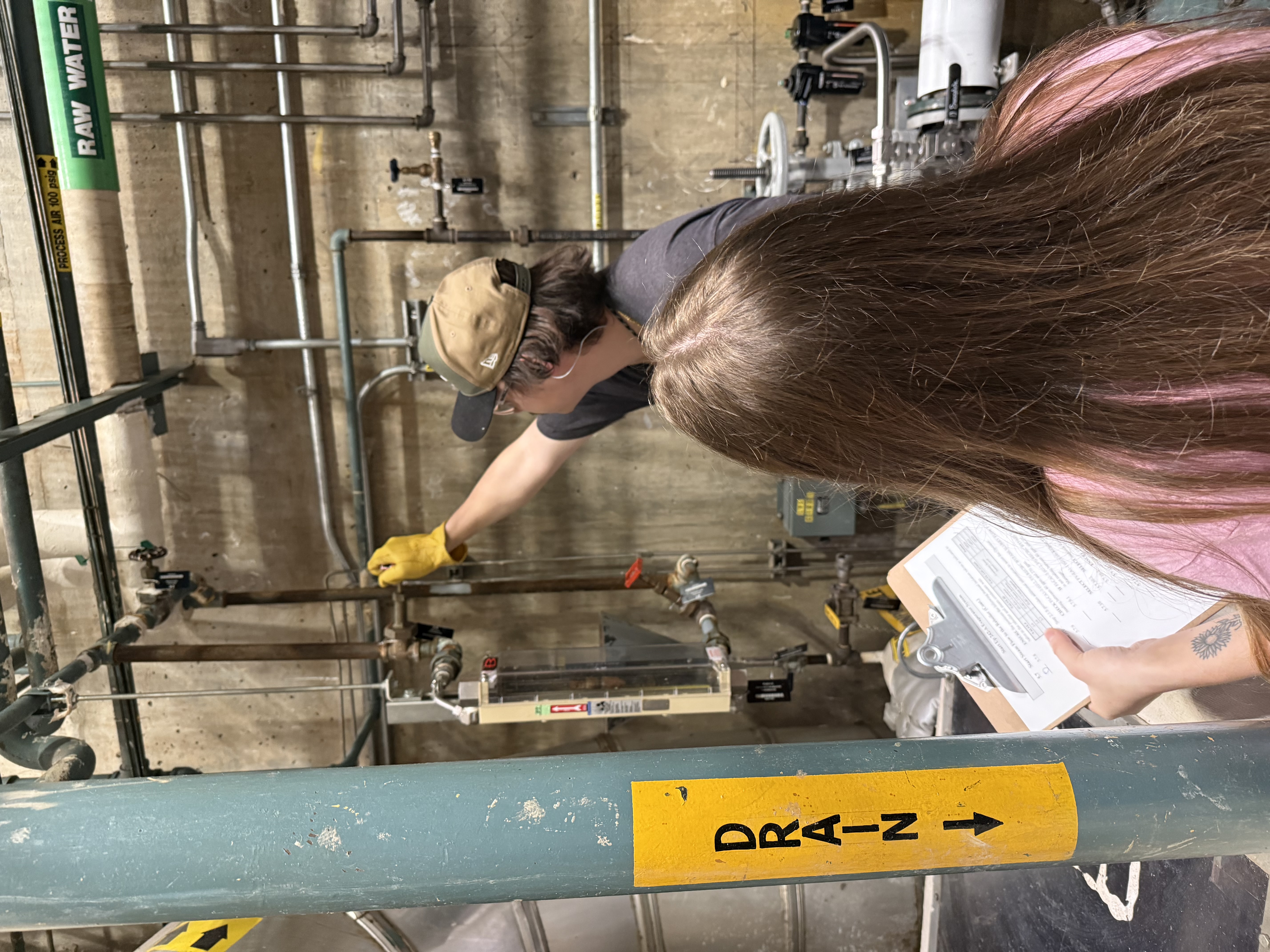 Employees inside of a steam facility working on pipes on the wall