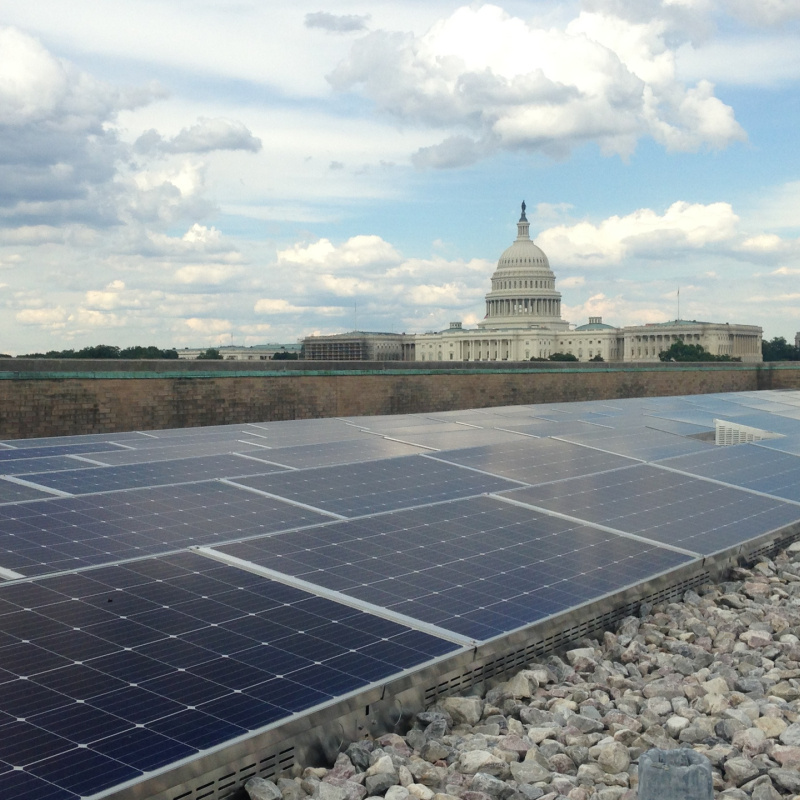 Rooftop solar panels in the foreground and the capital building in Washington DC in the background