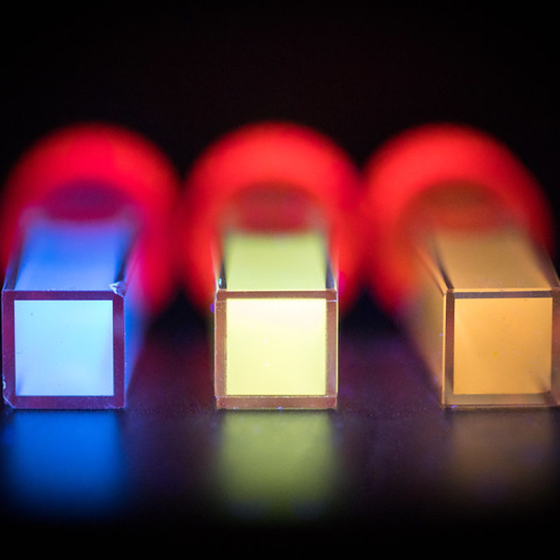 Three tubes lay on a black surface with brightly colored materials inside