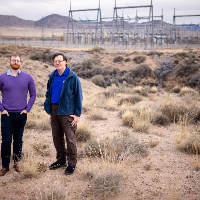 two men standing in desert field
