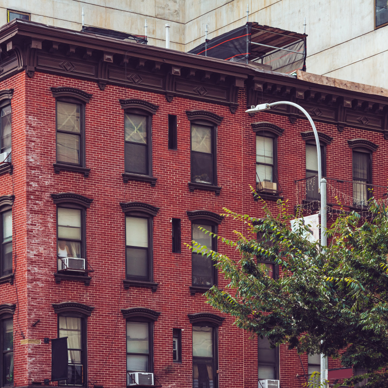 A multistory brick apartment building with a tree and streetlight.