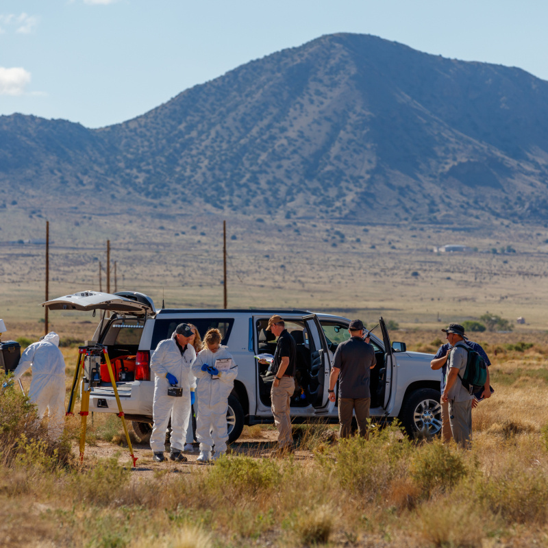 A group of technicians outside near a vehicle with a mountain in the background