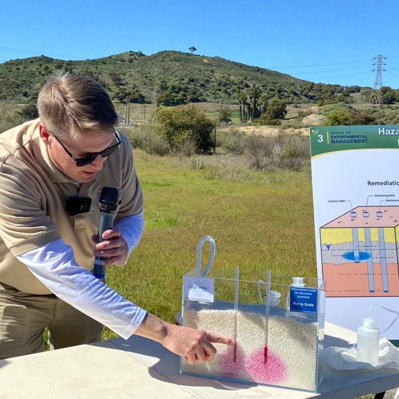 A person with a microphone pointing at a table display.