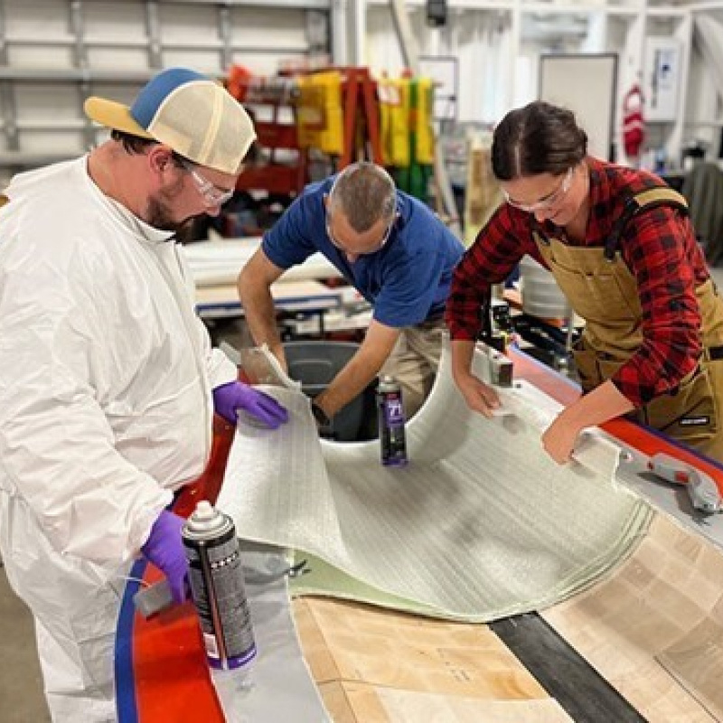 People in lab attire work on a mold of a wind turbine