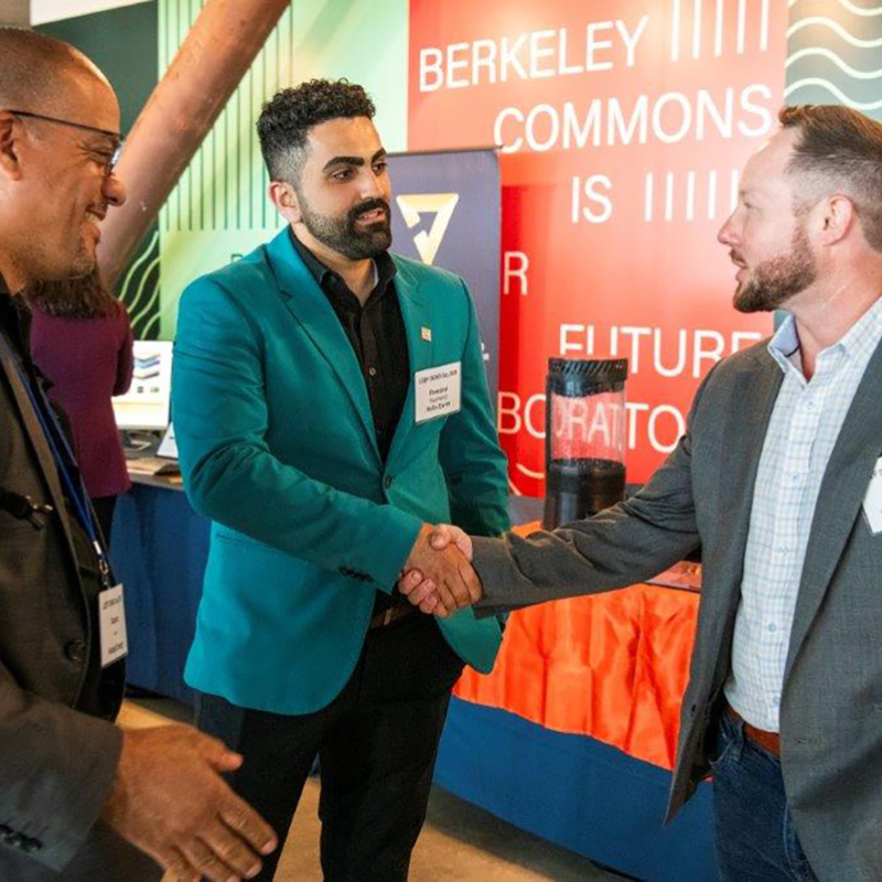 Three men greet one another at event