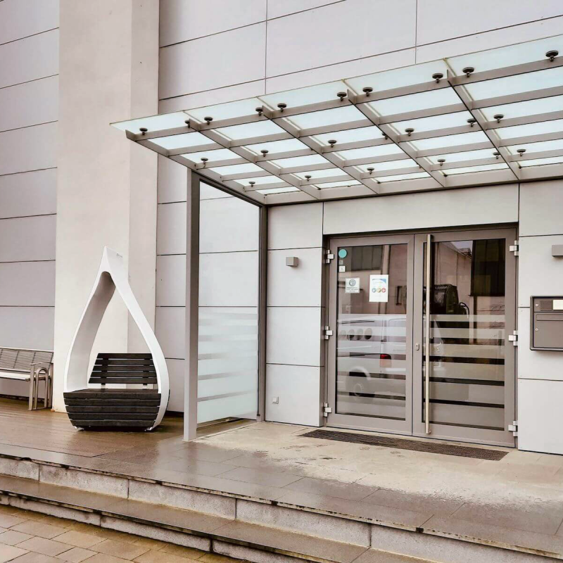 The front of a building with glass doors and a metal canopy at the top of two concrete steps.