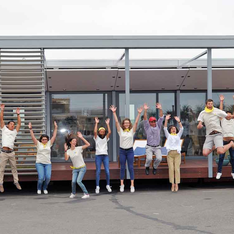 A group of students from a Build Challenge team jumping up in the air, facing the camera, in front of their competition house.