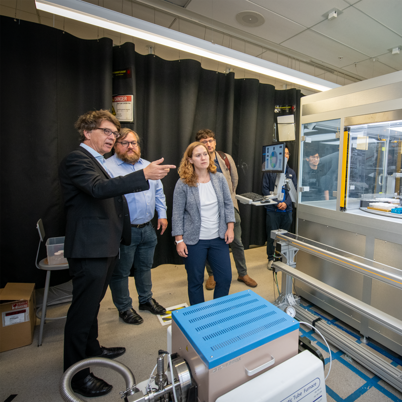 Researchers observe an automated robotic laboratory system performing experiments. 