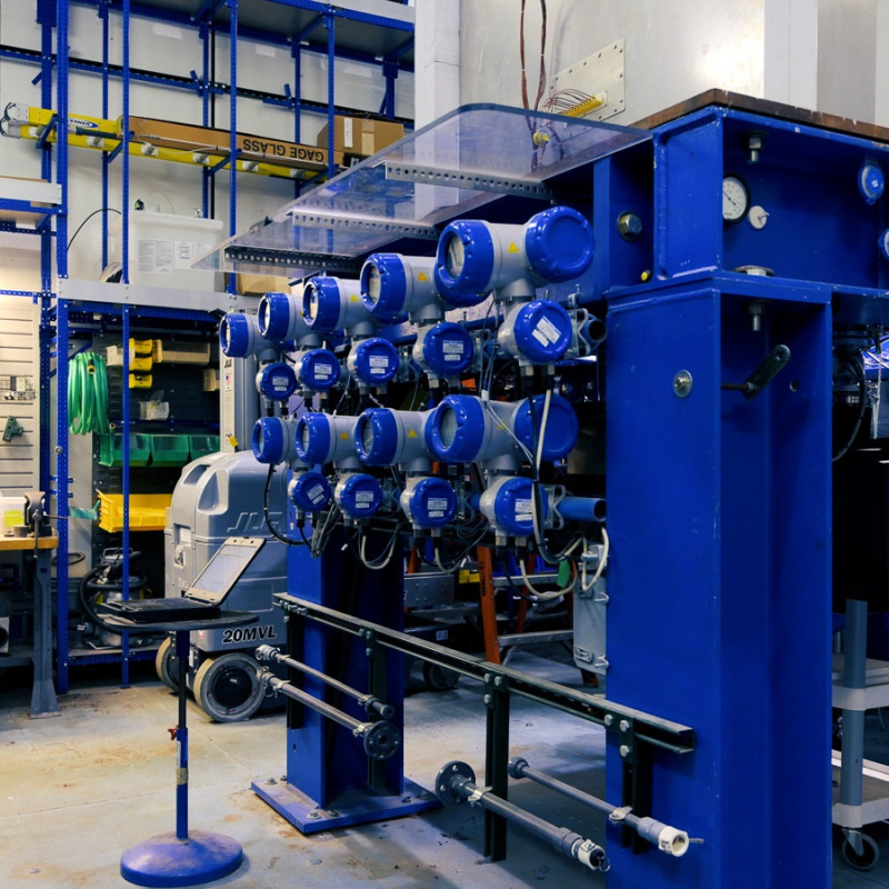A researcher at Argonne National Laboratory stands next to a large equipment assembly painted blue.