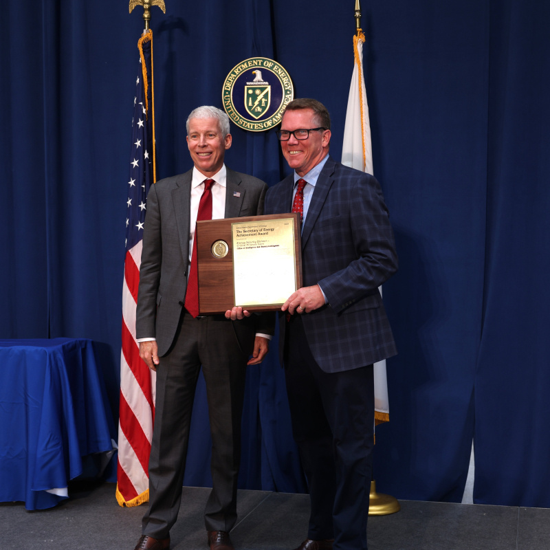 Two professionals holding an award posing for a photo together