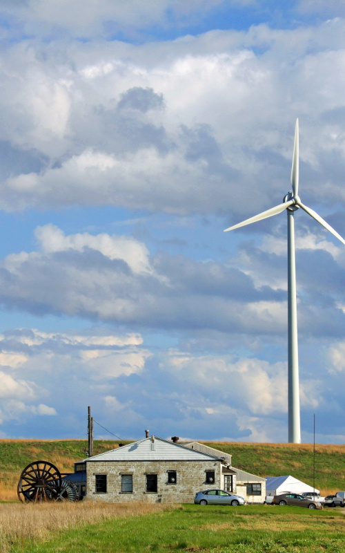 wind turbine on farmland against a cloudy but blue sky.