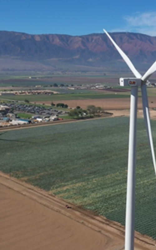 Two wind turbines in a large, open field.