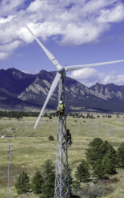 Two workers on a wind turbine with lattice tower construction.  