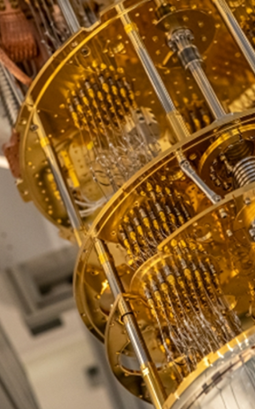 Photograph of part of a quantum computer consisting of gold plates connected by gold wires and silver tubes. 