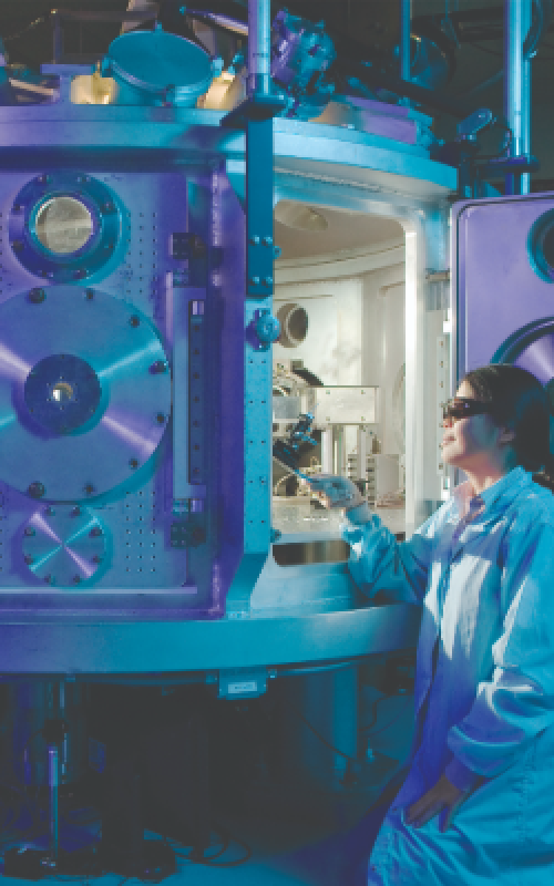 Woman in lab coat looking into large machinery (left); Man in orange shirt presenting to an audience. The banner behind him says "Innovation Showcase"