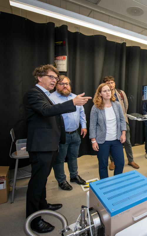Researchers observe an automated robotic laboratory system performing experiments. 