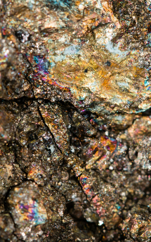 Close-up photo of dark brown stone dotted by bits of why and other bits of vibrant color