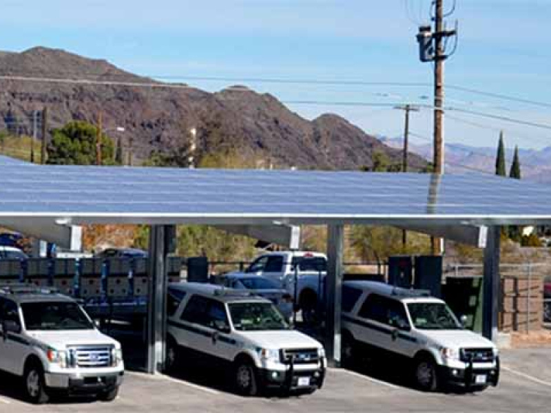 Cars parked under a roof of solar panels.