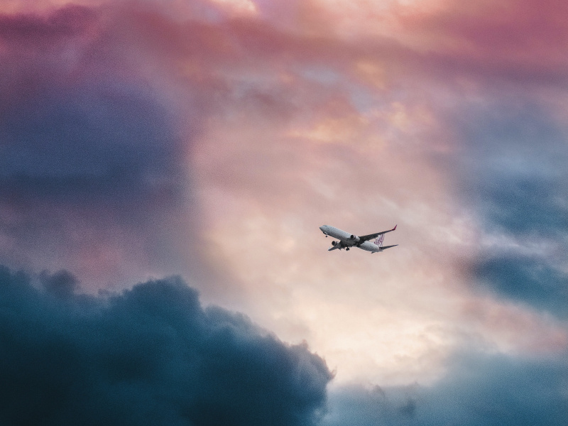 White plane flying through clouds. 