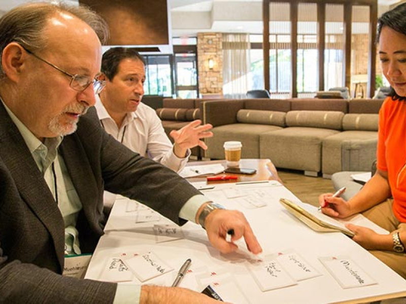 Image of three people, two males and a female, working together at a table.