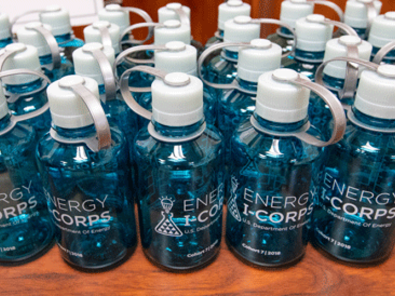 A line of water bottles with the Energy I-Corps logo on their sides