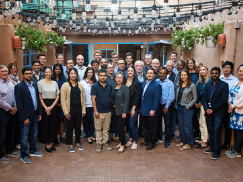 Men and women stand together for a group photo on an enclosed outdoor patio.
