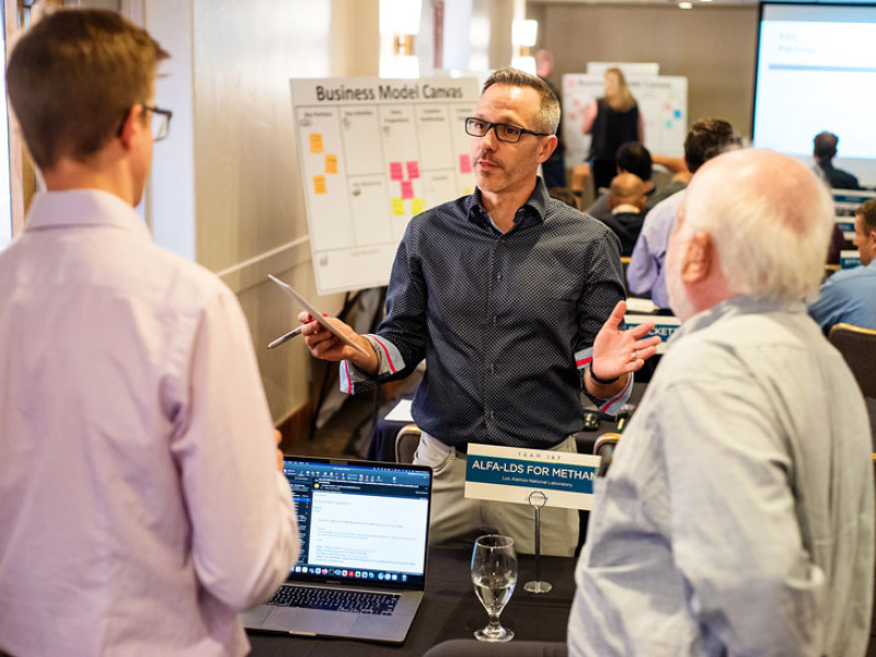 A trio of people talk candidly in a meeting room.