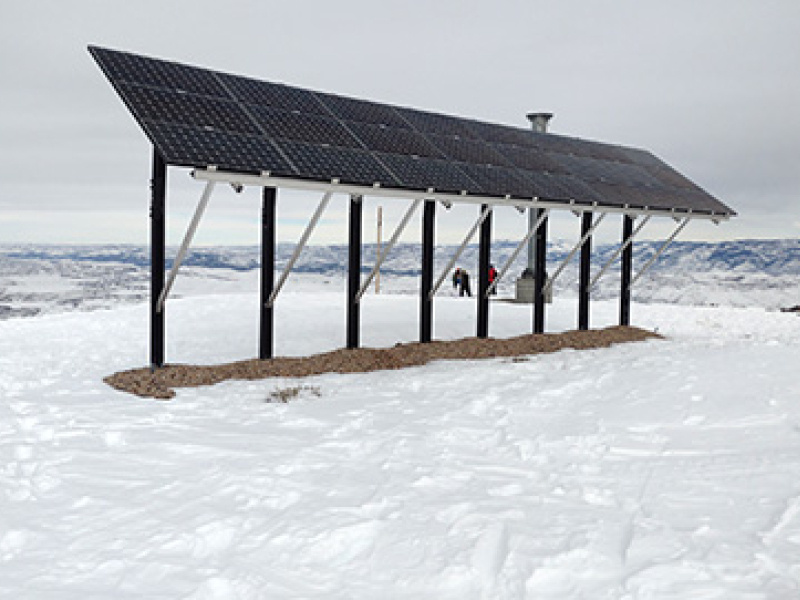 A solar array in the mountains surrounded by snow.