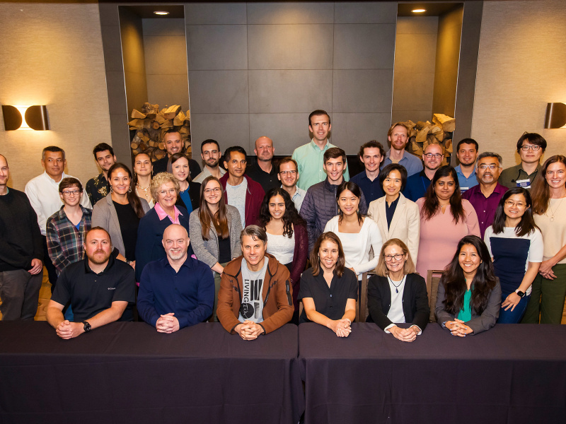 A group of 34 people pose and smile for the camera.