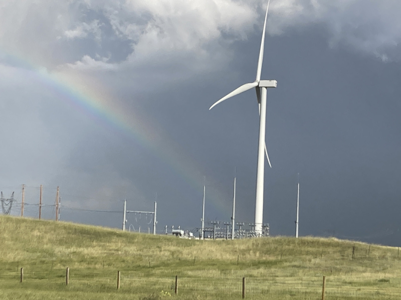 A wind turbine with a rainbow behind it