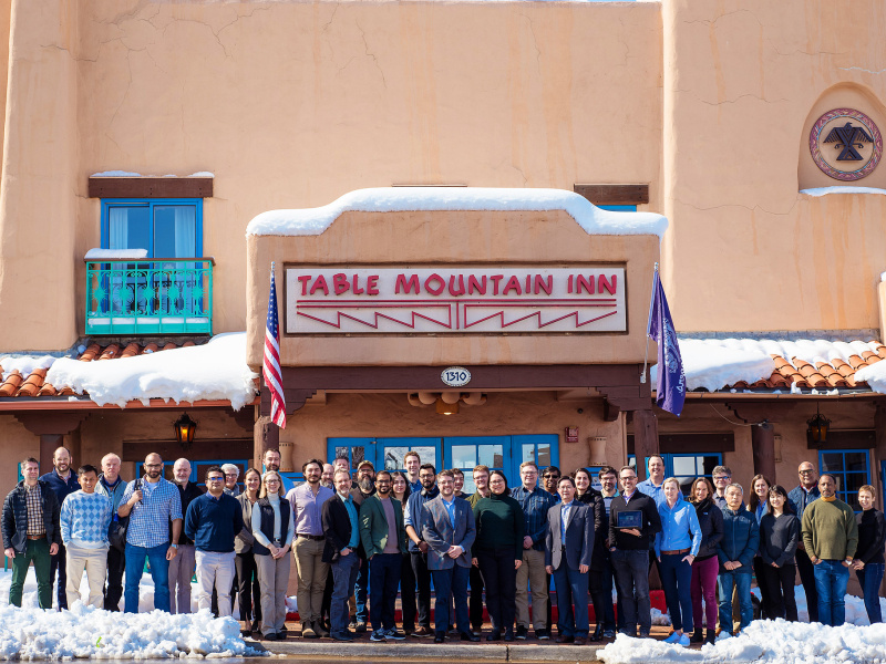 A group of 40 people stand and pose in front of a building.