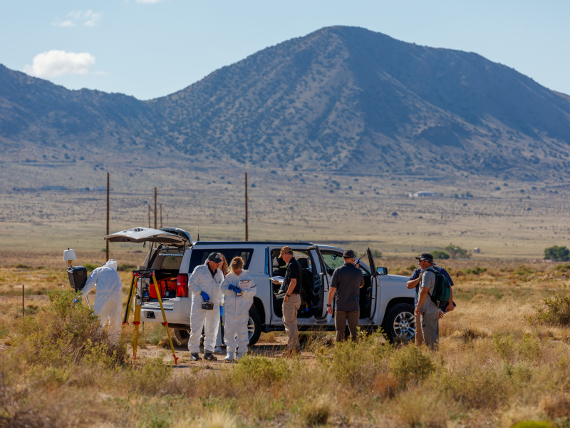 A group of technicians outside near a vehicle with a mountain in the background