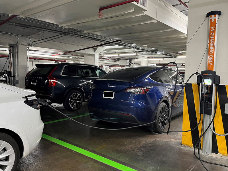 Electric vehicles plugged into a charging station in a parking garage.