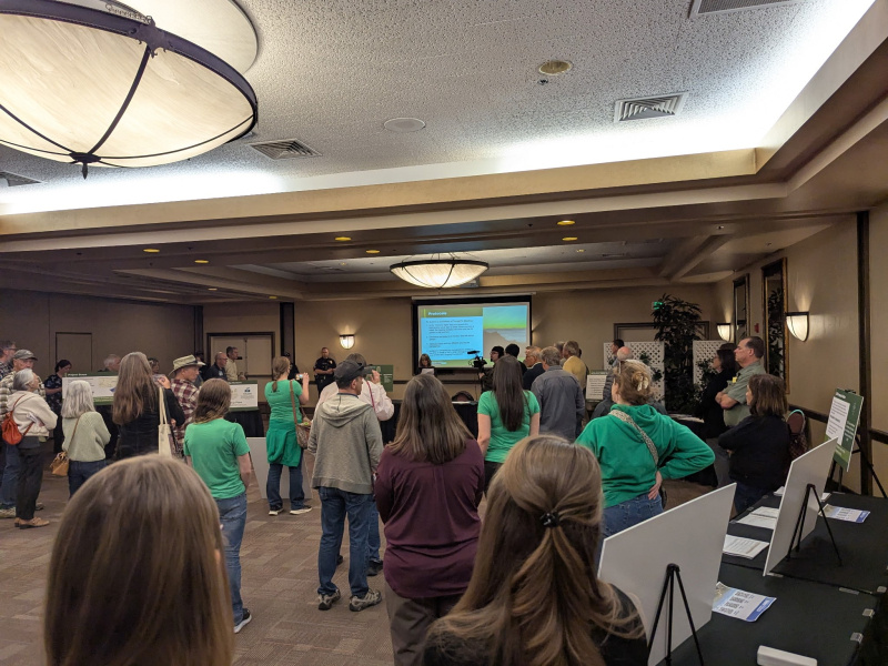 A group of people in a room face the front of the room where a presentation is being given