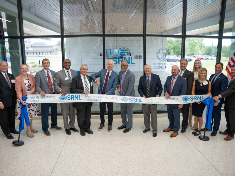 A group of people posing for a picture behind a rope about to be cut to open a Center