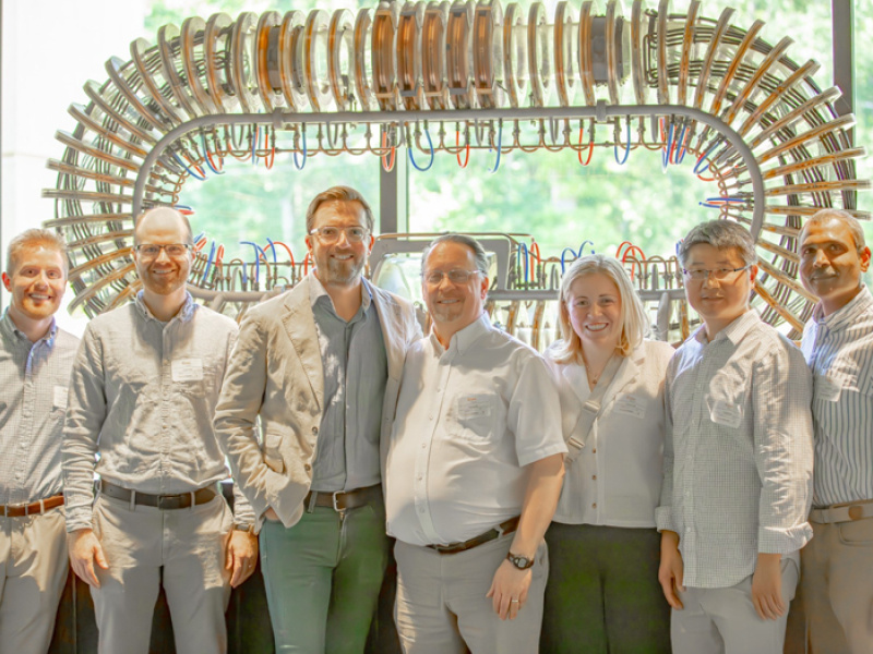 The Thea Energy team in front of DOE’s Princeton Plasma Physics Laboratory model stellarator exhibited at the 1958 Atoms for Peace conference in Geneva, Switzerland.