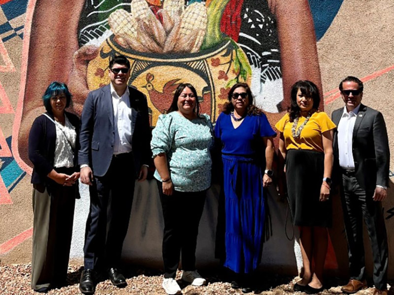 Group stands in front of mural