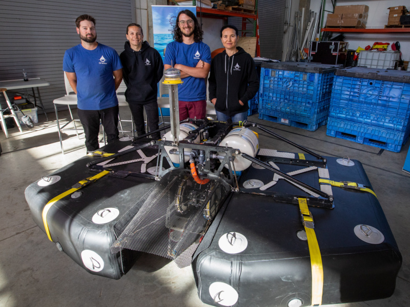 Oneka team stands next to wave-powered desalination device