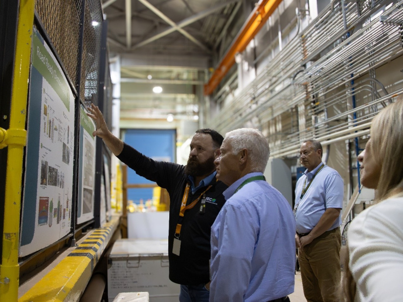 EM Assistant Secretary taking a tour of a fuel storage facility building with lots of pipes and signs on the wall
