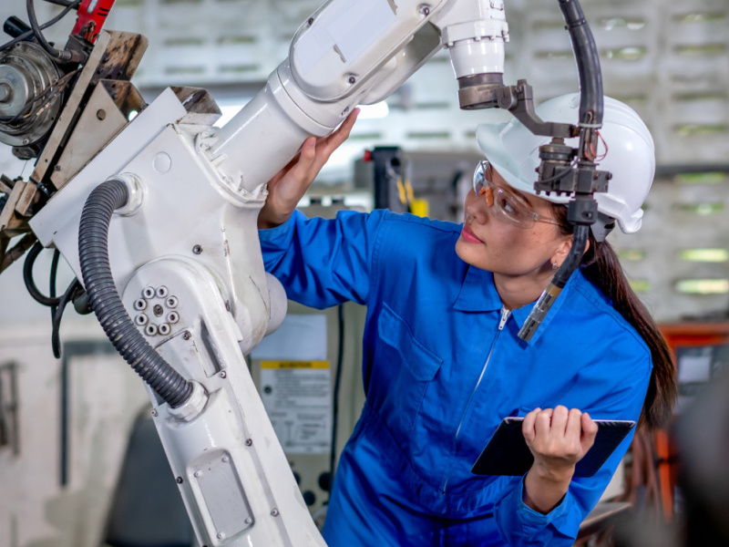 An engineer inspects an industrial robotic arm.