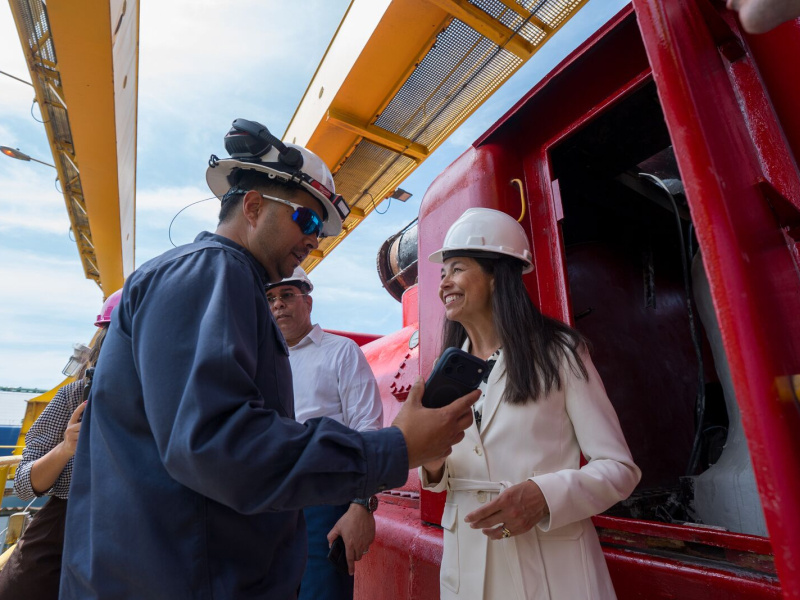 Power plant personnel wearing hard hats speak beside large industrial equipment during a facility tour.